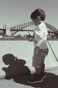Side view of boy playing with shadow with sydney harbor bridge in background