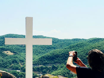 Rear view of man photographing against sky