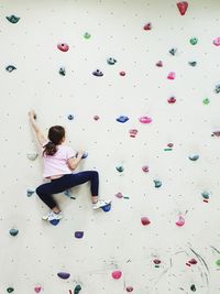 Rear view of girl climbing wall