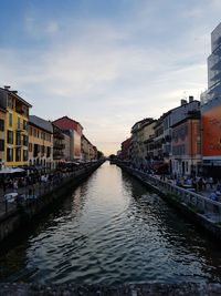 Canal in city against sky