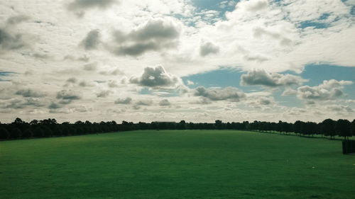 Scenic view of grassy field against cloudy sky