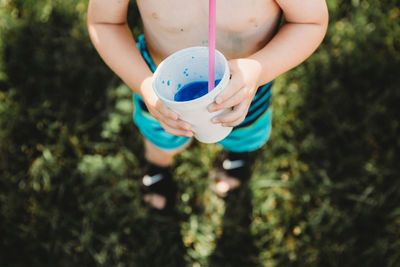 Above perspective of young boy drinkning blue snowcone