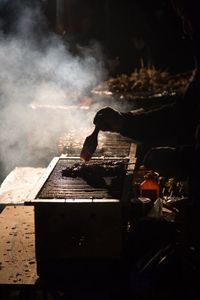 Cropped hand brushing oil on barbecue at market stall