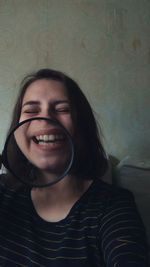 Portrait of a smiling young woman against wall