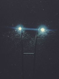 Low angle view of lit street lights at night