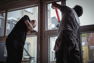 Two people are repairing a plastic window, sealing the cracks with silicone. person