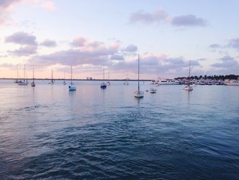 Boats in sea against cloudy sky