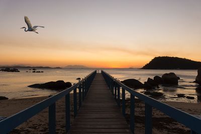 Pier over sea against sky during sunset