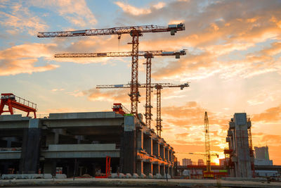 Low angle view of construction machinery against sky during sunset