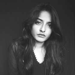 Close-up portrait of a beautiful young woman over black background