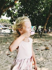 Cute girl eating food against trees