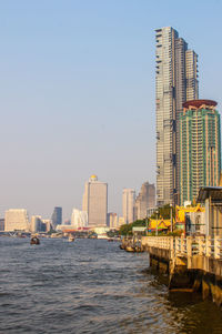 Buildings by river against sky in city