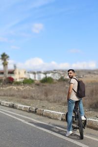 Rear view of woman walking on road against sky