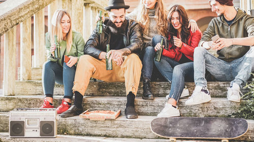 Friends having beer while sitting on steps