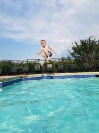 Full length portrait of boy jumping over swimming pool