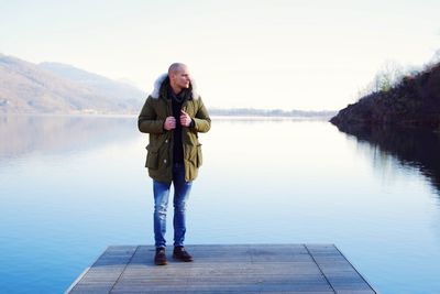 Rear view of woman standing by lake