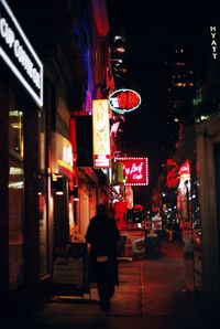 Rear view of woman in illuminated city at night