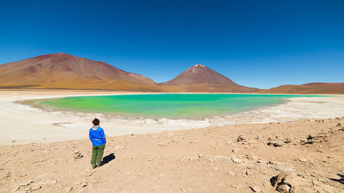 Rear view of man on desert against blue sky