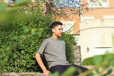 Boy standing by tree against plants