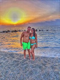 Full length of friends enjoying at beach against sky during sunset