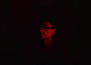 Portrait of young man against black background