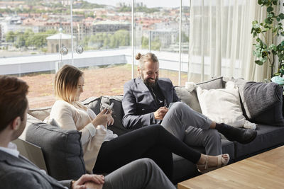 Coworkers using cell phones on sofa