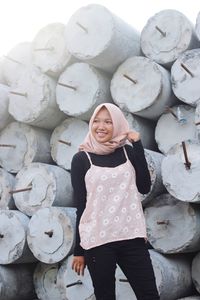 Smiling young woman looking away standing against concrete