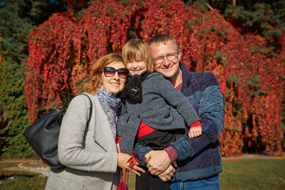 Portrait of parents standing with daughter at park during autumn