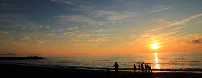 Silhouette people at beach during sunset