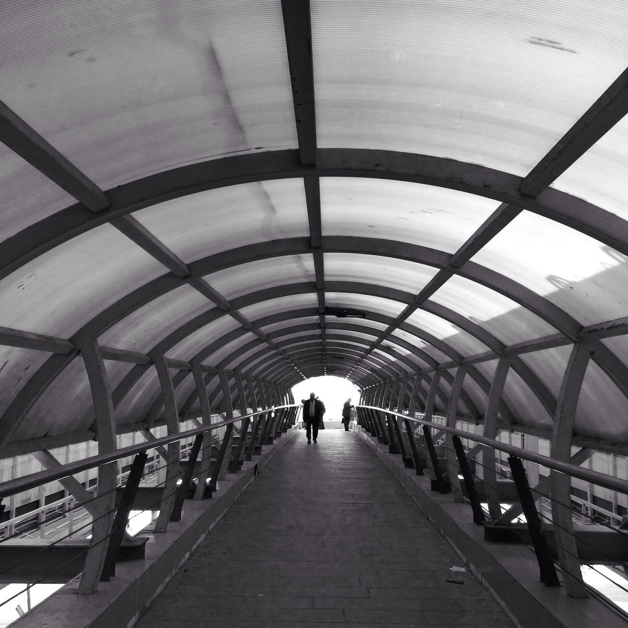 the way forward, indoors, architecture, diminishing perspective, built structure, ceiling, vanishing point, walking, connection, arch, men, railing, incidental people, walkway, footbridge, pedestrian walkway, in a row, tunnel, bridge - man made structure