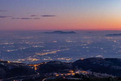 Aerial view of illuminated cityscape against sky during sunset