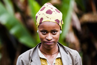 Portrait of young woman standing outdoors against plant