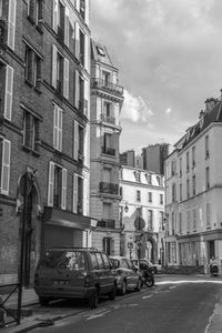 Cars on street in city against sky