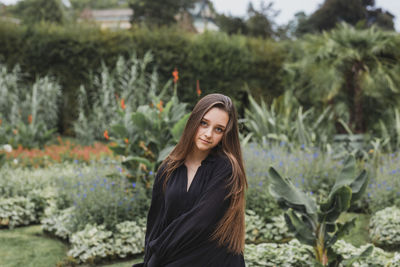 Portrait of smiling young woman standing against plants