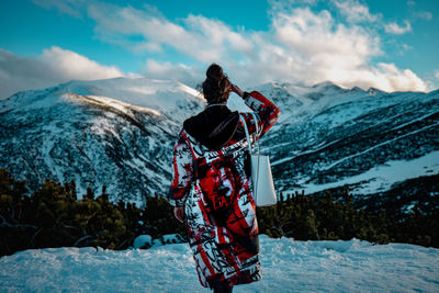 Rear view of person standing on snowcapped mountain