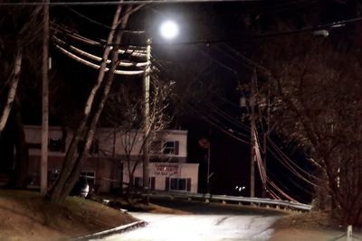 Illuminated street light by building at night