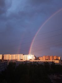 Rainbow over buildings in city against sky