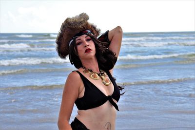 Portrait of woman standing at beach against sky