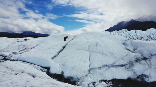 Silhouette person on snowcapped mountain against cloudy sky