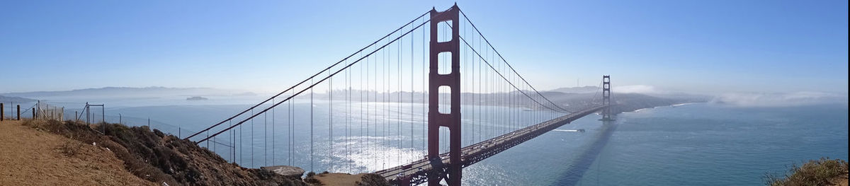 Suspension bridge over sea against sky