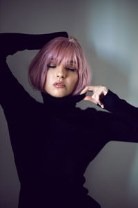 Close up portrait of a woman with pink hair and a black sweater on the background