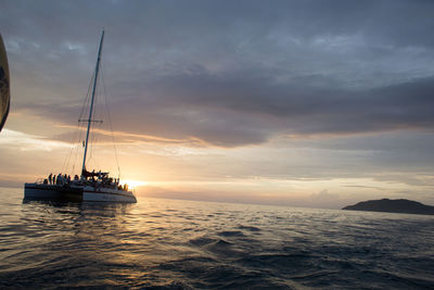 Boat sailing in sea against cloudy sky