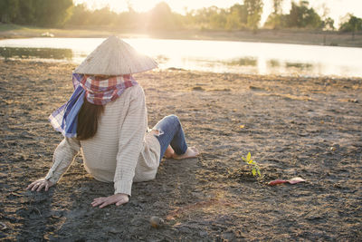 Woman sitting on field by lake