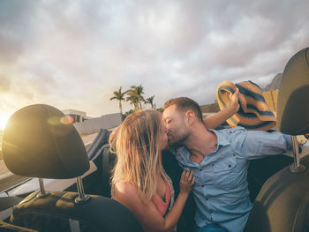 Young couple kissing against sky