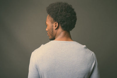 Rear view of man looking away against gray background