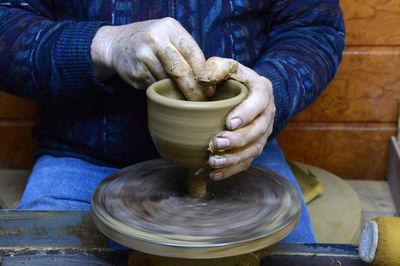 Craftsperson shaping pot on pottery wheel