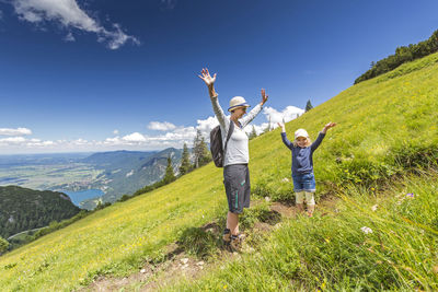 Happy mother and daughter standing on landscape against sky