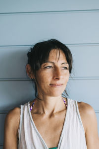 Thoughtful woman standing against wall