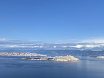 Aerial view of snowcapped mountains by sea against sky