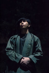 Young man standing against black background